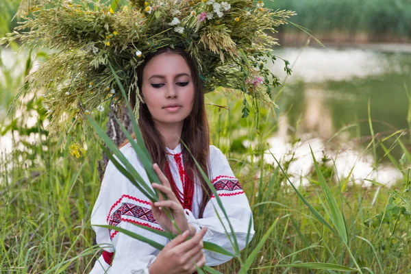 Beautiful girl in embroidery shirt and wreath of wild flowers. — Stock Photo, Image