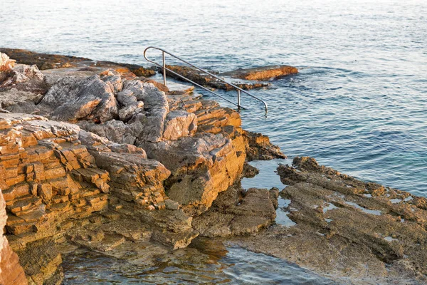 Solnedgången klippstrand med stege för simning i Istrien, Kroatien. — Stockfoto