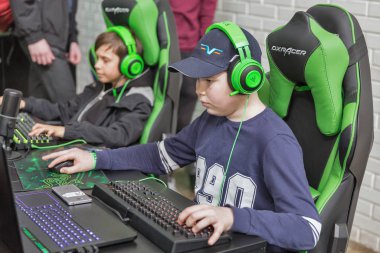 KYIV, UKRAINE - APRIL 13, 2019: Teenagers playing computer games at DXRacer booth, a gaming console chair company, during CEE 2019, the largest electronics trade show of Ukraine in Tetra Pack EC.