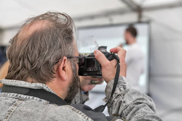Kyiv, Ukrayna - 19 Mayıs 2018: Çok amaçlı kalıcı bir sergi kompleksi olan Ulusal Expocenter 'daki Yemek ve Şarap Festivali sırasında erkek fotoğrafçı çalışıyor ve şarap tadıyor.
