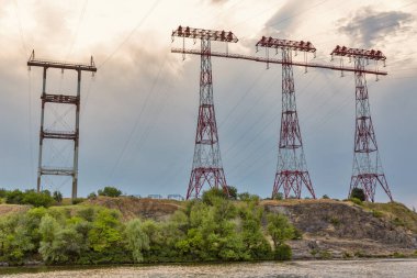 Ukrayna 'nın Khorytsia adasında günbatımında yüksek voltajlı elektrik hatları kuleleri.