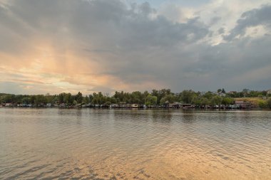 Gün batımında Khorytsia adası yakınlarındaki Dinyeper nehir kıyısındaki balıkçı köyünün tekne ve yat kutuları..