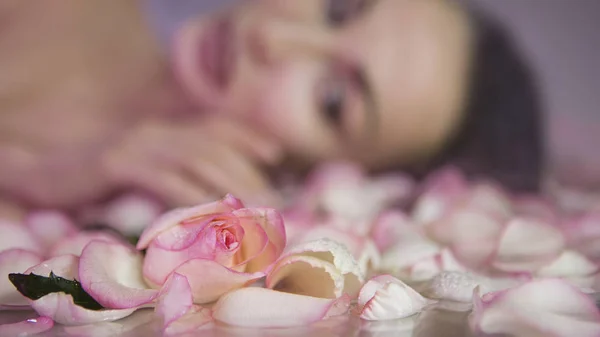 Pétalos de rosa fresca y capullo de rosa. Blurred Mujer cara con clea — Foto de Stock