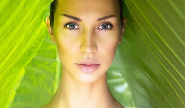 Beautiful Woman face with Natural nude make-up on a tropical lea