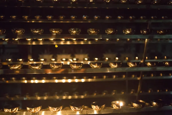 Fiamma di candela primo piano. Molte candele in un tempio buddista. Religi — Foto Stock