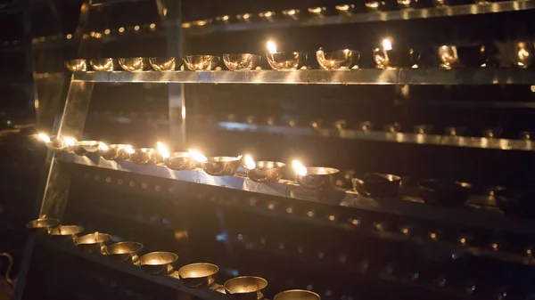 Chama de vela close-up. Muitas velas em um templo budista. Religi — Fotografia de Stock