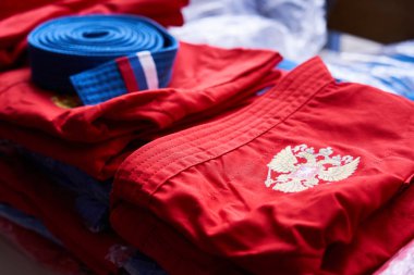red sport uniform with coat of arms of Russian federation folded and lying on the table with many other equipment clipart