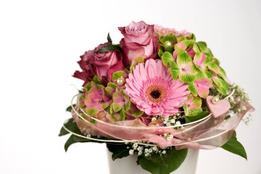 Beyaz vazoda gül ve gerberalar bulunan güzel çiçek buketi, sade bir arka planda.