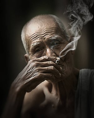 Yaşlı adam sigarasının tadını çıkarıyor.