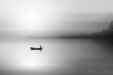 gün batımında denizde teknede adam