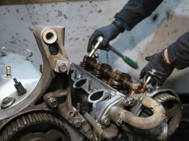 Bağlantı çubuğu, piston ve silindir bloğu parçalanmış durumda. Adamın eli motoru tamir ediyor.