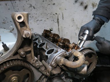 Bağlantı çubuğu, piston ve silindir bloğu parçalanmış durumda. Adamın eli motoru tamir ediyor.