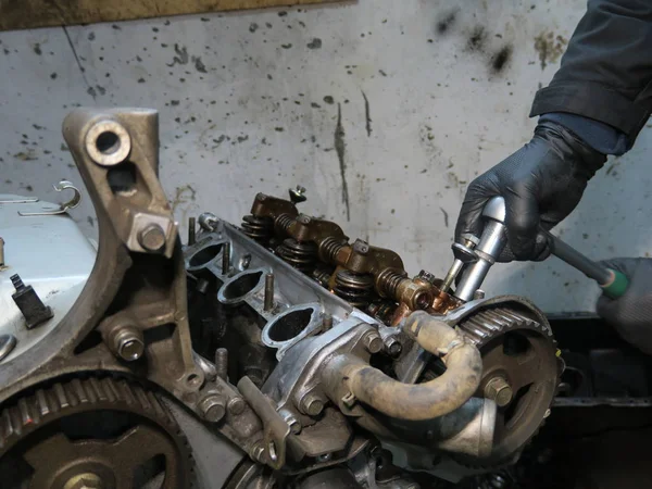The connecting rod, piston and cylinder block in a disassembled condition. Man s hand fixing a engine