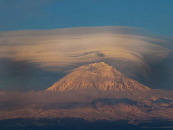 Paysage avec le volcan Arenal qui plane sur le nuage lenticulaire. Nuages lenticulaires au-dessus des volcans Kamchatka au coucher du soleil — Photo