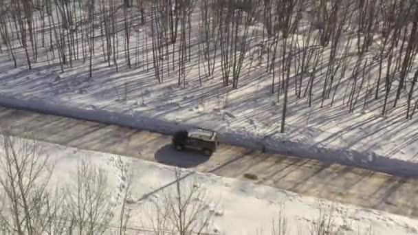 Aerial Drone View of a Crossover Driving on forest winter Road during a Cloudy Day. — Wideo stockowe