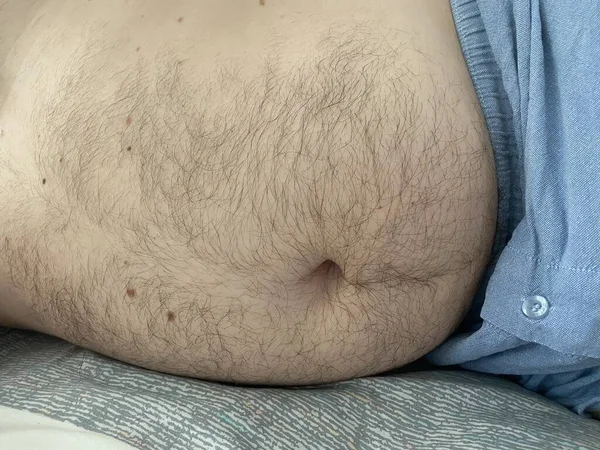 Funny fat man showing his big belly. He puts a hand on the belly