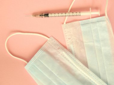 COVID-19. Yığının üzerinde yüz maskeleri var. Pembe arka plan. Eczanede yüz maskesi sıkıntısı var. Karantina geçmişi. Korunmak için tıbbi maskeler. Tehlikeli bir virüs. Yüz maskeleri teke tek