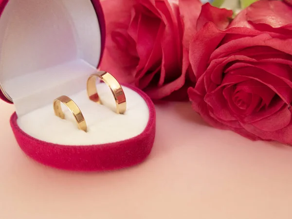 Hochzeitsfeier mit rosa Rosenstrauß, goldenen Eheringen in der rosa Box, isoliert auf rosa Hintergrund. Konzept von Liebe und Romantik. — Stockfoto