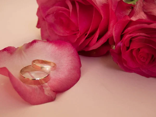 Hochzeitsfeier mit rosa Rosenstrauß, goldene Trauringe isoliert auf rosa Hintergrund. Konzept von Liebe und Romantik. — Stockfoto