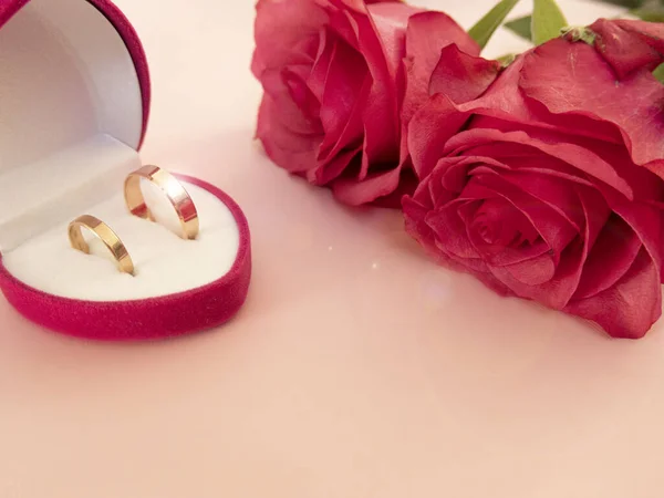 Wedding celebration with pink rose bouquet, gold wedding rings in the pink boxe, isolated on pink background. Concept of love and romance. Royalty Free Stock Photos