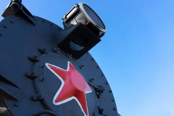 Kızıl yıldızlı eski Sovyet buharlı lokomotifi. Buharlı lokomotifin buhar kazanının ön tarafında bir projektör var.