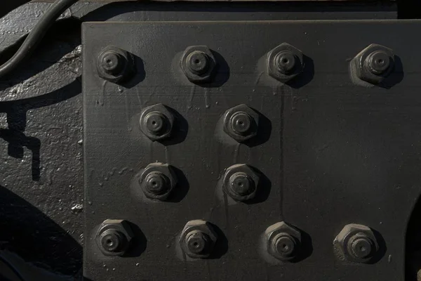 Siyah boyanmış civata ve fındıklar büyük bir metal teçhizatı bir arada tutar. Endüstriyel bağ dokusuna yakın çekim