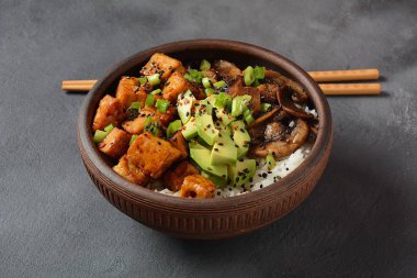 Tatlı, baharatlı, çıtır çıtır ve teriyaki soslu kızarmış tofu avokado, kızarmış mantar, susam tohumu ve pilav ile servis edilir. Sağlıklı vegan yemeği, glütensiz.