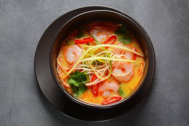 Laksa Çorbası içinde taze fasulye filizi, salatalık, limon, kırmızı biber ve kişniş bulunan karidesli Hint cevizli köri çorbası.