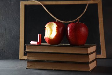 Kırmızı elma ve koyu arkaplanda bir yığın kitap. Okul konseptine dönelim.