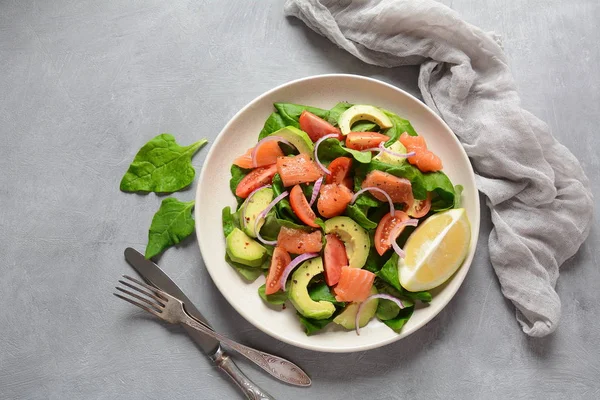 Mediterranean Avocado Salmon Salad with spinach, cherry tomatoes, avocado and red onion dressing. Concept for a tasty and healthy meal. Vegan food