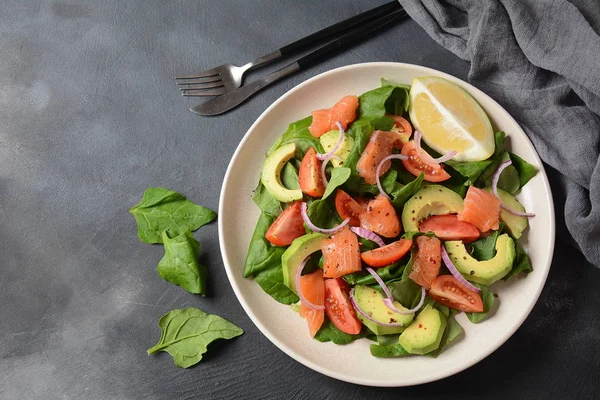 Mediterranean Avocado Salmon Salad with spinach, cherry tomatoes, avocado and red onion dressing. Concept for a tasty and healthy meal. Vegan food