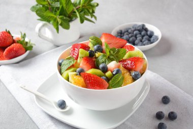 Bowl of healthy fresh colorful fruit salad on wooden background. Top view.Fruit salad with strawberry, blueberry, sweet cherry, kiwi.Vegetarian food concept. Rustic wooden background