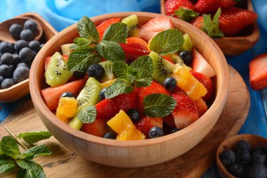 Bowl of healthy fresh colorful fruit salad on wooden background. Top view.Fruit salad with strawberry, blueberry, sweet cherry, kiwi.Vegetarian food concept. Rustic wooden background