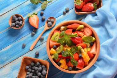 Bowl of healthy fresh colorful fruit salad on wooden background. Top view.Fruit salad with strawberry, blueberry, sweet cherry, kiwi.Vegetarian food concept. Rustic wooden background