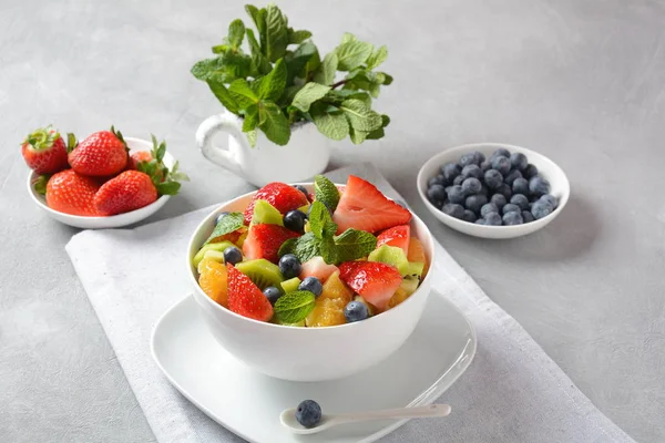 Bowl of healthy fresh colorful fruit salad on wooden background. Top view.Fruit salad with strawberry, blueberry, sweet cherry, kiwi.Vegetarian food concept. Rustic wooden background