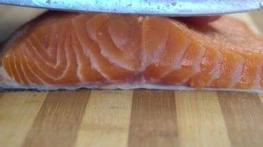 Şef yavaş çekimde suşi pişirmek için somon filetosunu dilimlerle kesiyor. Tahta tahtada kırmızı balık kesen adam yakın plan. Şef Kırmızı Balığı Kesiyor, En Lezzetli Et Yavaş Hareketi. Makro. Kesme tahtasında somon filetosu kes.