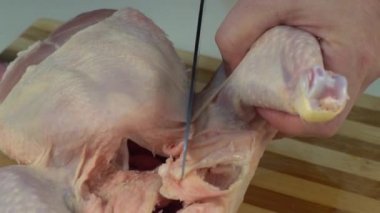 Bütün bir çiğ tavuğu porsiyonun içine oymak. Kızarmış tavuk budu için tavuk budu. Çiğ bir tavuğu doğramak. Şefin elleri tavuğu yavaş çekimde kesiyor. Erkek eli bıçakla tavuk eti kesiyor..