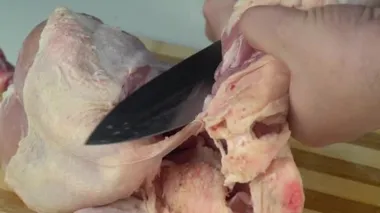 Bütün bir çiğ tavuğu porsiyonun içine oymak. Kızarmış tavuk için tavuk kanadı. Çiğ bir tavuğu doğramak. Şefin elleri tavuğu yavaş çekimde kesiyor. Erkek eli bıçakla tavuk eti kesiyor..