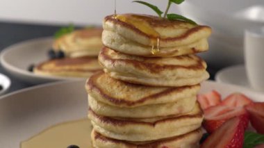 Lezzetli tereyağlı krep yığınına akçaağaç pekmezi dök. Yakın çekim görüntüsü, yavaş çekim görüntüsü. Yabanmersinli krep ve damlayan kahvaltı makrosu..