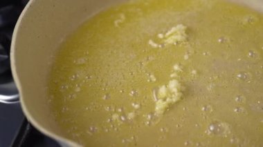 Sarımsak pişiriliyor ve erimiş tereyağıyla kızartılıyor. Tavadaki erimiş tereyağında sarımsak kızartılıp kızartılıyor..