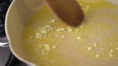 Sarımsak pişiriliyor ve erimiş tereyağıyla kızartılıyor, sonra tavada karıştırılıyor, yakın plan.