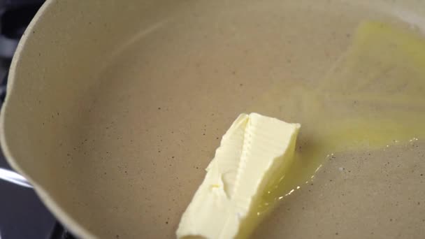 黄油在炉子上的平底锅里融化得嘎吱嘎吱作响 靠近点 慢动作 黄油在热烤架表面融化 一立方体的天然黄油在热锅里融化了 — 图库视频影像