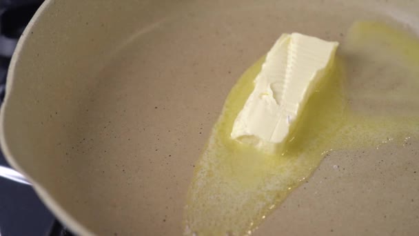 黄油在炉子上的平底锅里融化得嘎吱嘎吱作响 靠近点 慢动作 黄油在热烤架表面融化 一立方体的天然黄油在热锅里融化了 — 图库视频影像