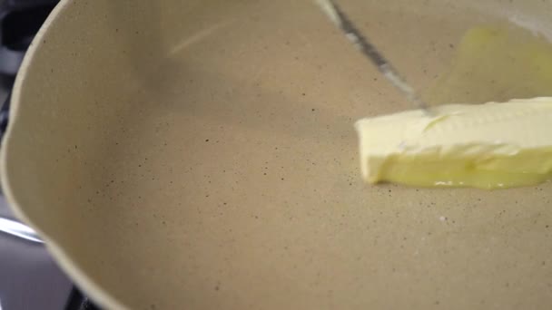 厨师在热锅上涂上黄油 在锅上融化黄油 在刀端涂上黄油 黄油在炉子上的平底锅里融化得嘎吱嘎吱作响 用慢动作把一立方体的天然黄油融化在热锅里 — 图库视频影像