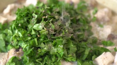 Bir yığın kişniş yapraklı güveç tuzla tatlandırılıyor.