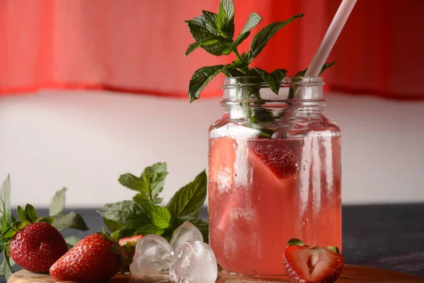 Fresh strawberry lemonade with ice and mint in glass. Cold summer drink. Sparkling glass with berry cocktail.Strawberry mojito . Cold refreshing cocktail