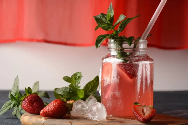 Fresh strawberry lemonade with ice and mint in glass. Cold summer drink. Sparkling glass with berry cocktail.Strawberry mojito . Cold refreshing cocktail