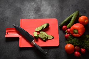 Mutfak tahtasındaki sebzeleri doğramak. Salata hazırlamak ya da pişirmek