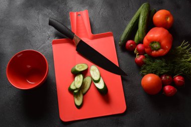 Mutfak tahtasındaki sebzeleri doğramak. Salata hazırlamak ya da pişirmek