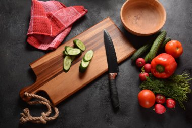 Mutfak tahtasındaki sebzeleri doğramak. Salata hazırlamak ya da pişirmek